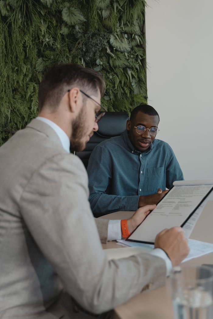 The Art of Drawing Readers In: Your attractive post title goes here Two men in a modern office setting discussing a document during a business meeting.